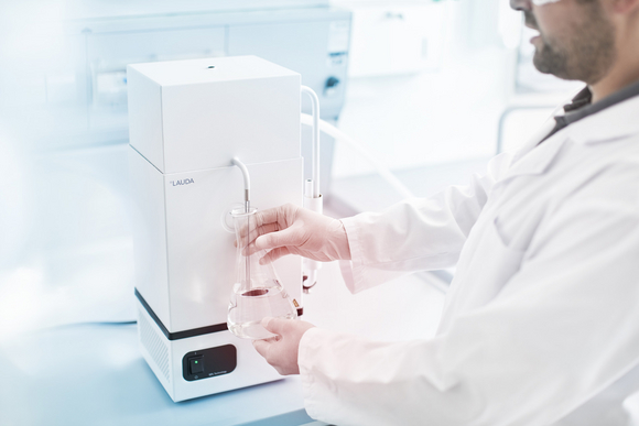 A laboratory technician removes deionized water from the still.