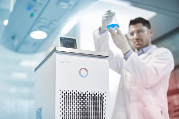 Un empleado de laboratorio sostiene un matraz de reactivos con líquido a temperatura controlada.