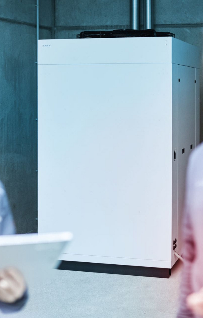 A group of people stands in front of a LAUDA constant temperature device.