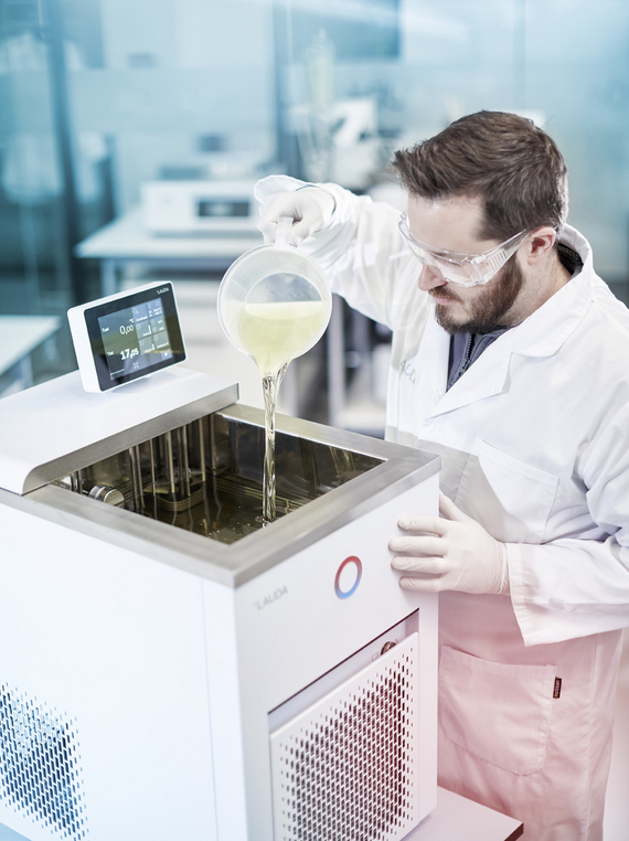 A man pours heat transfer liquid into a LAUDA constant temperature equipment.