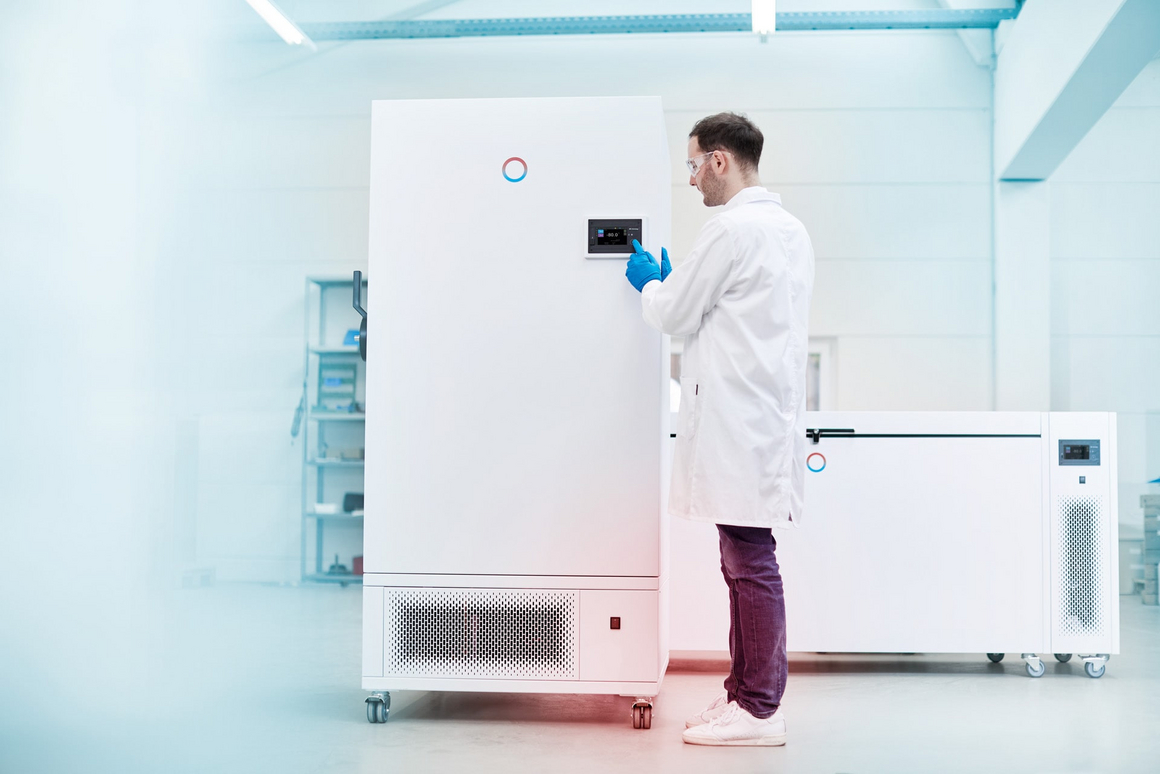 Un empleado de laboratorio realiza ajustes en un congelador del tamaño de una persona.