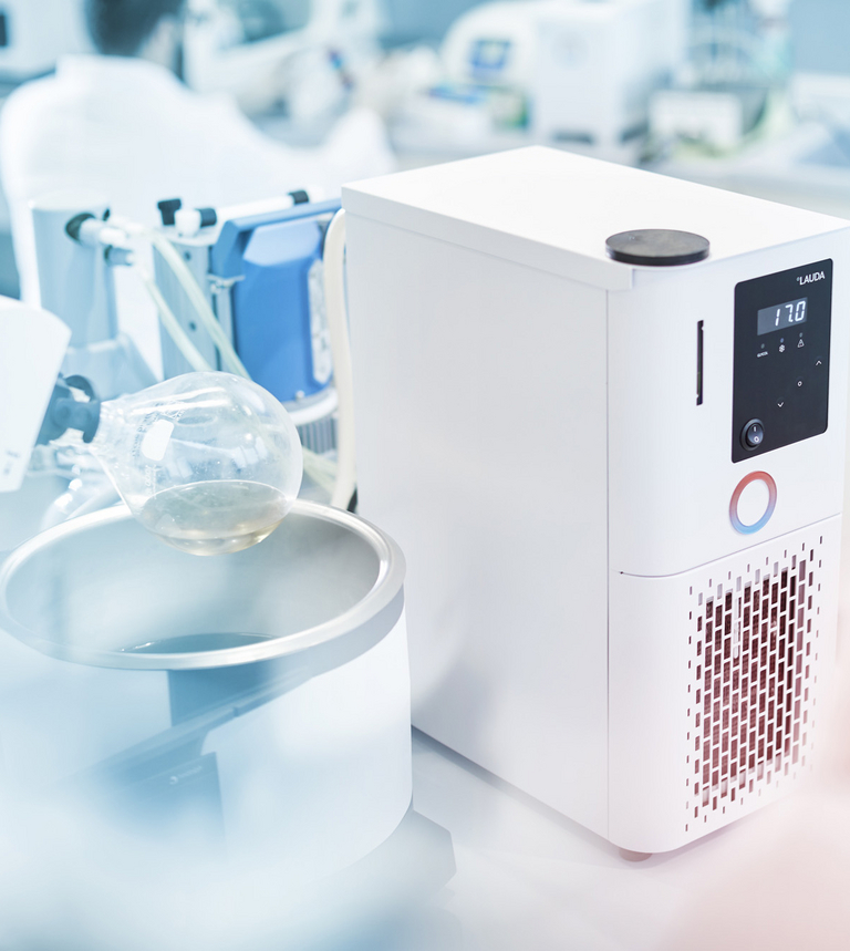 Un equipo de termorregulación LAUDA con una muestra de laboratorio en un matraz de fondo redondo se encuentra en un laboratorio.